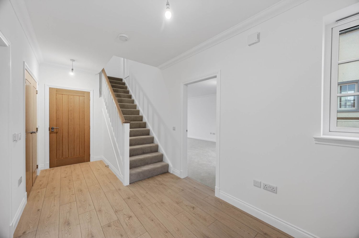 Bright modern hallway with wooden staircase and light wooden flooring.