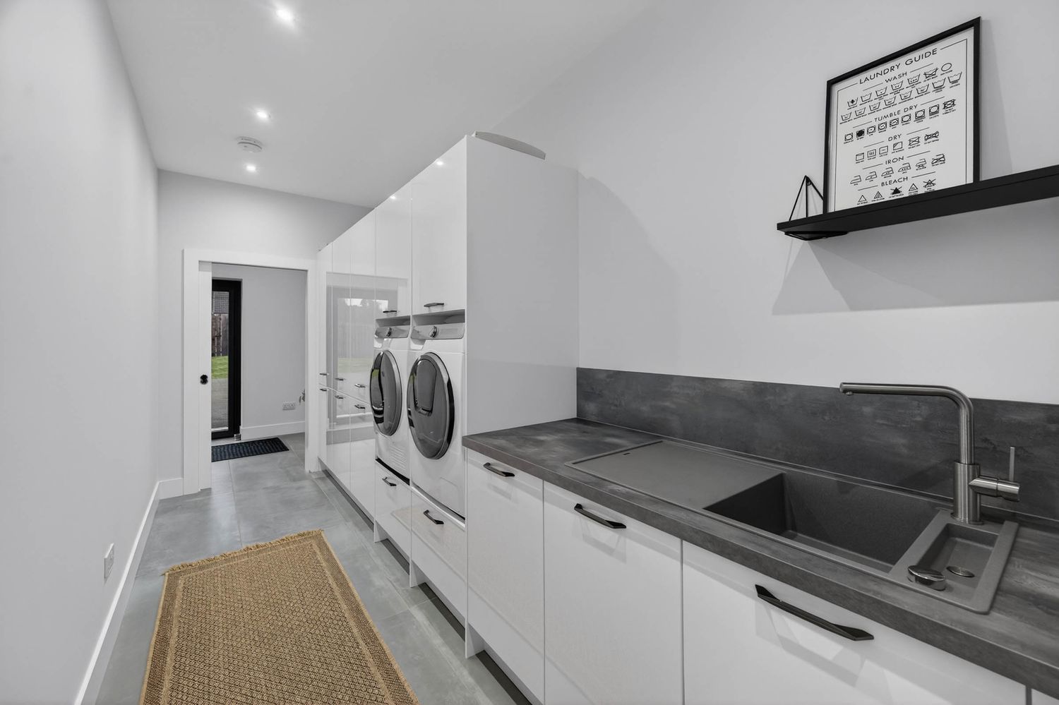 Modern white kitchen renovation with sleek cabinets, stainless appliances, and wood-look flooring.