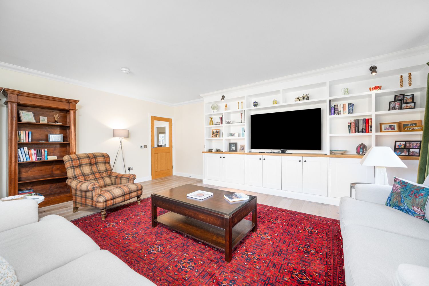 Cozy living room featuring built-in entertainment center, white sofa, oriental rug, and wooden furniture with bookshelves.