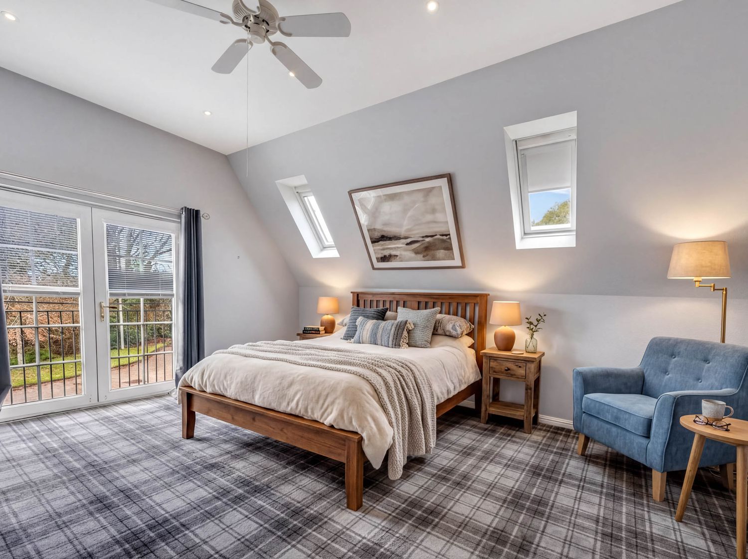 Panoramic view of master bedroom showing wood furniture, blue accent chair, and multiple windows.
