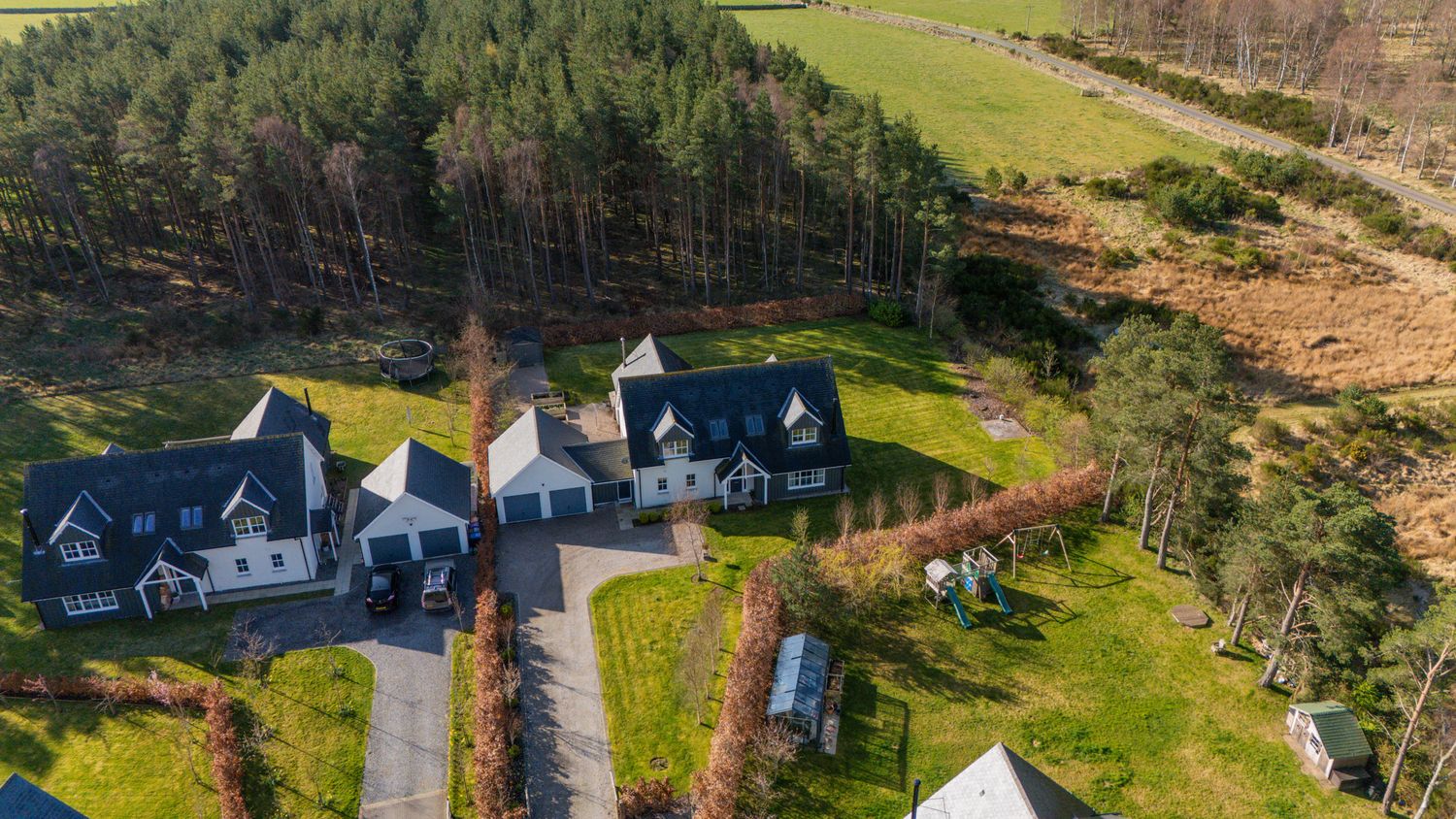 Aerial view of luxury homes nestled in a scenic coastal landscape with forest and grassland.