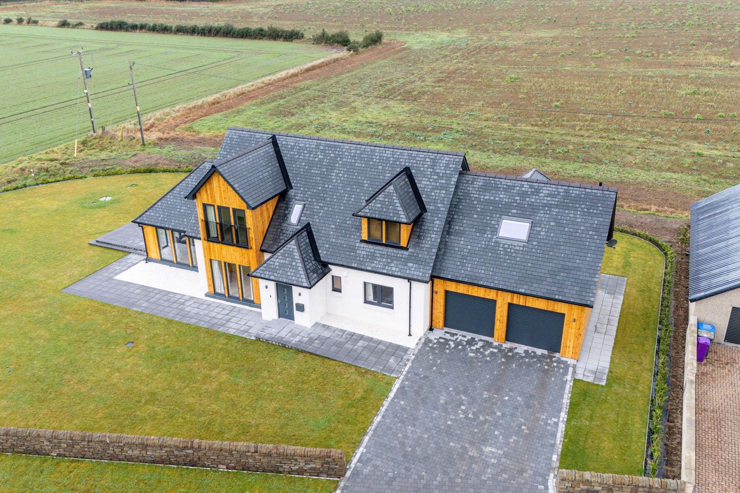 Contemporary white and wood house with dormer windows viewed from aerial perspective.