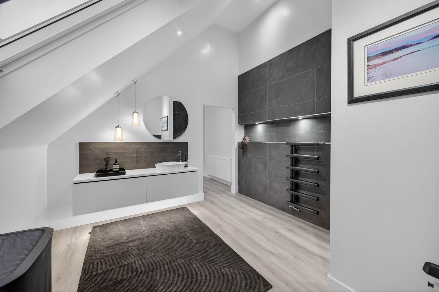 Modern interior hallway with white walls, recessed lighting, and dark flooring leading to multiple rooms.