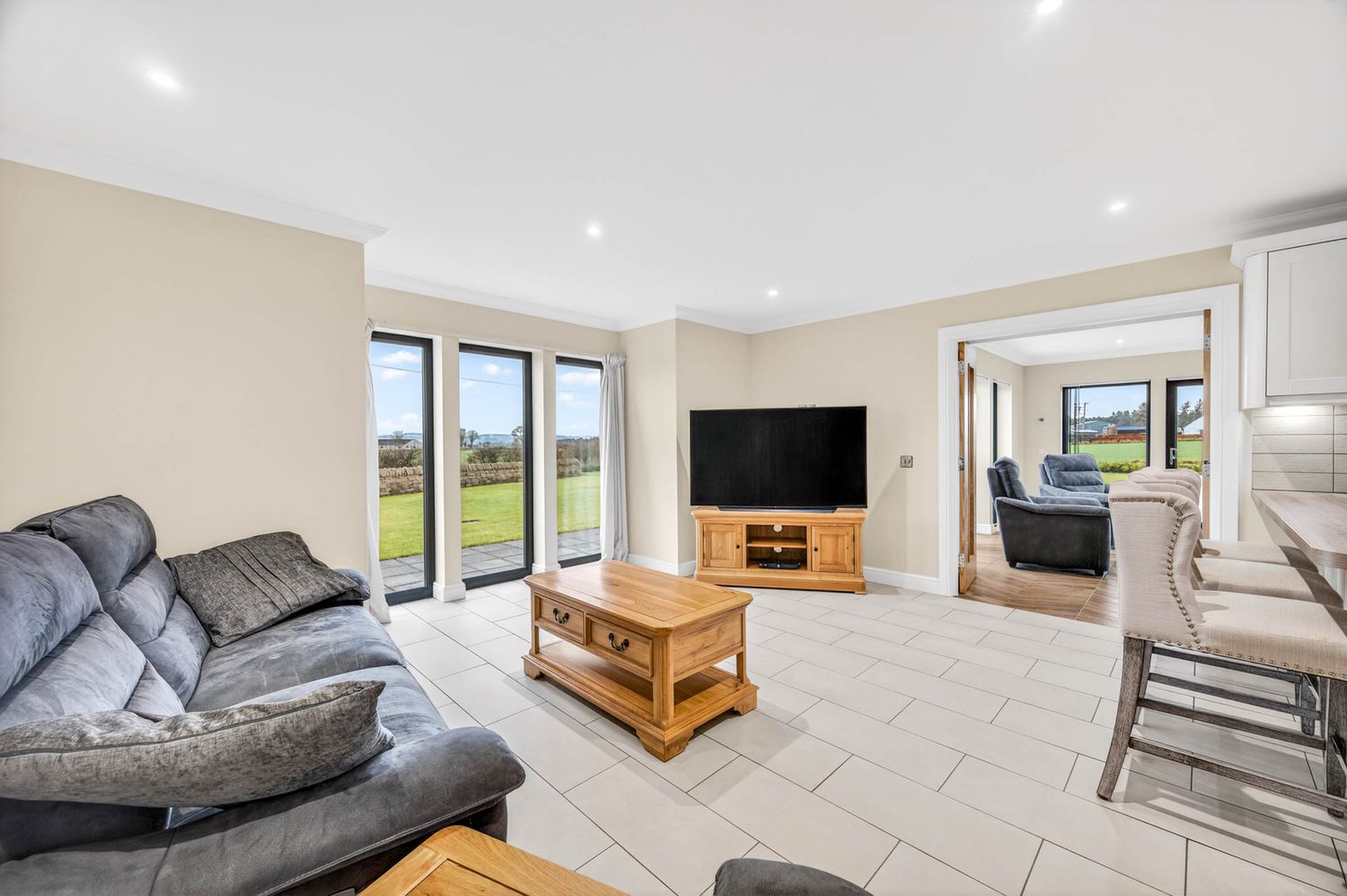 Spacious open concept living area with tiled flooring, recessed lighting, and modern furnishings.