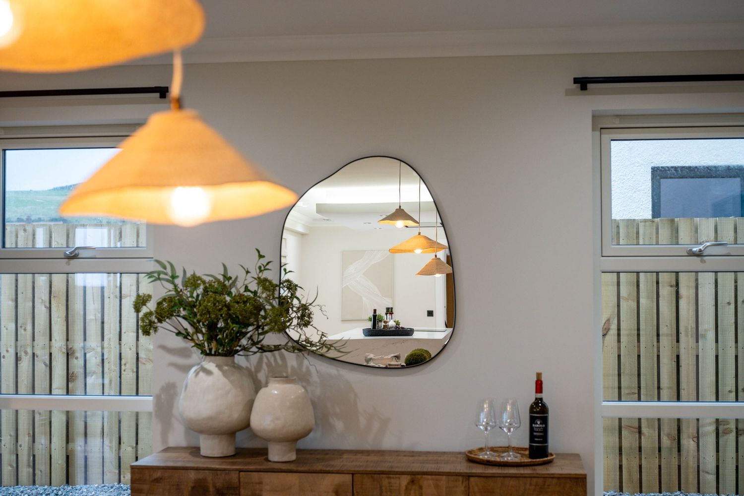 Orange pendant lamp illuminates a dining area with window views.