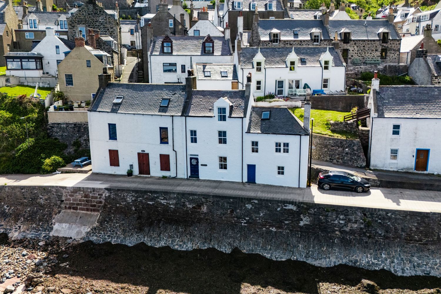Waterfront village with traditional white Scottish houses lined along the coastal seawall.
