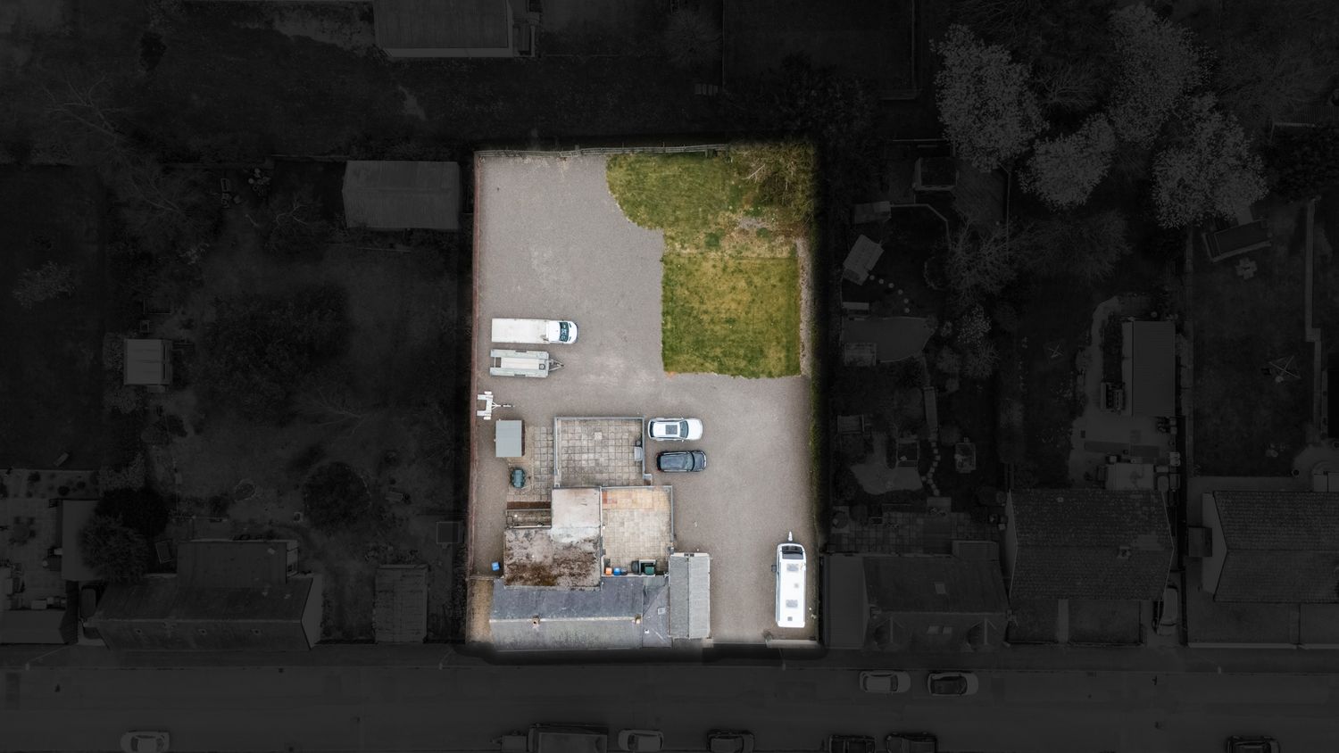 Aerial view of a storage facility parking lot with scattered vehicles and containers seen through a dark frame.