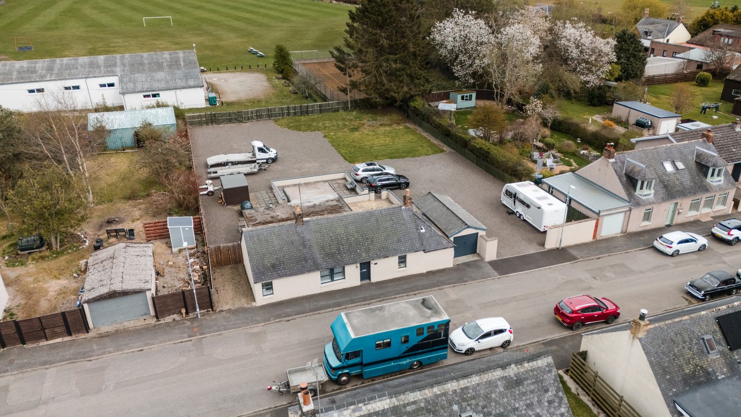 Aerial view of mobile homes and parked vehicles in a residential area with a bright blue trailer visible on the street.