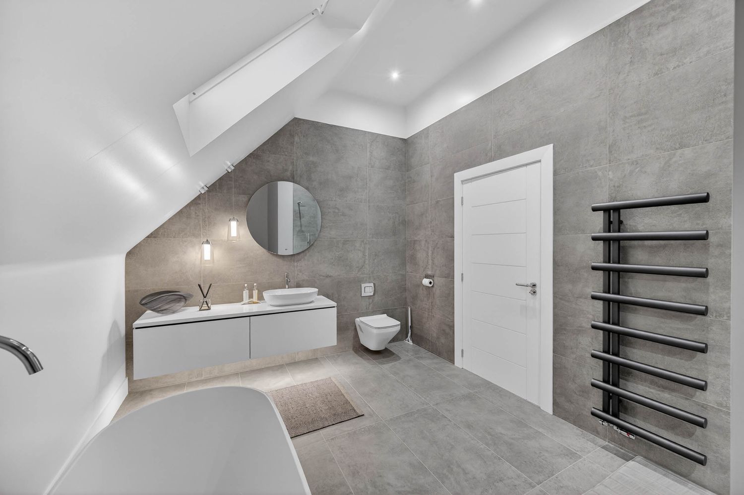 Modern bathroom interior with gray concrete walls, black towel racks, and recessed lighting creating a sleek minimalist design.