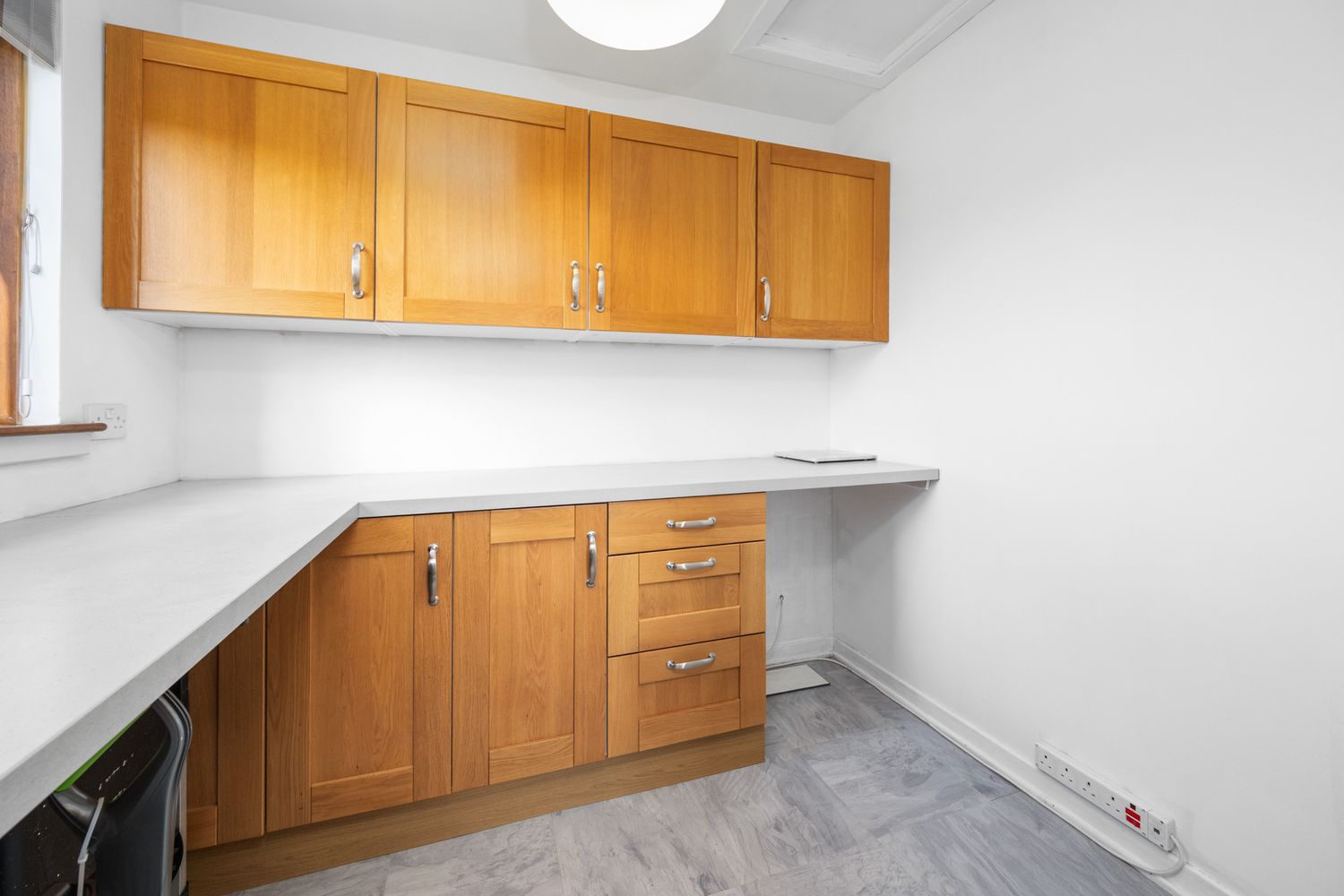 Small kitchen with wooden cabinets and white countertops features minimalist design and grey marble flooring.