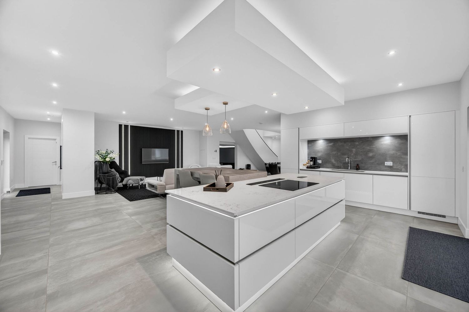 Minimalist open concept kitchen with white cabinetry, gray flooring, and modern lighting fixtures.