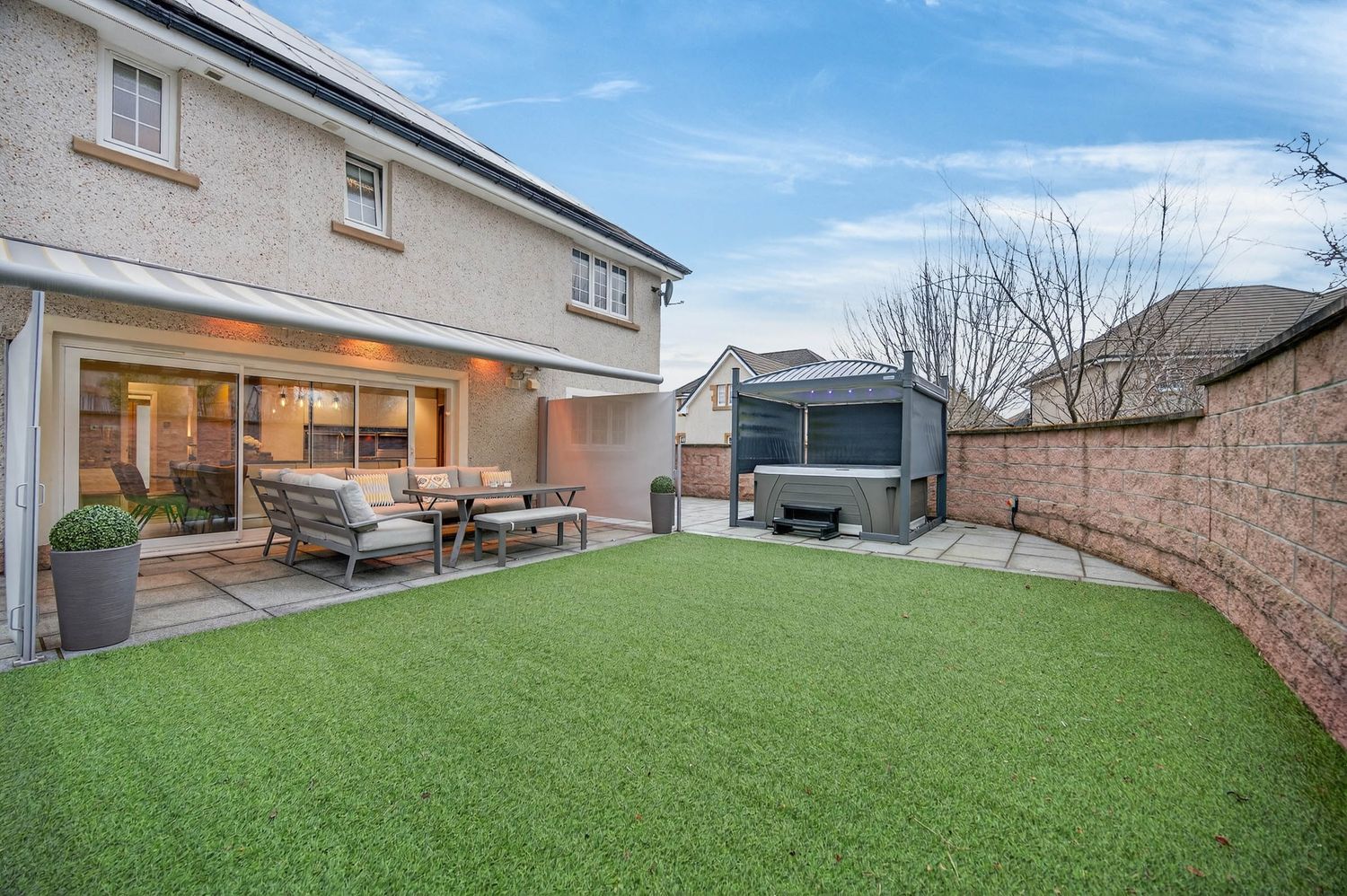 Daytime exterior view of modern house with large lawn and patio area.