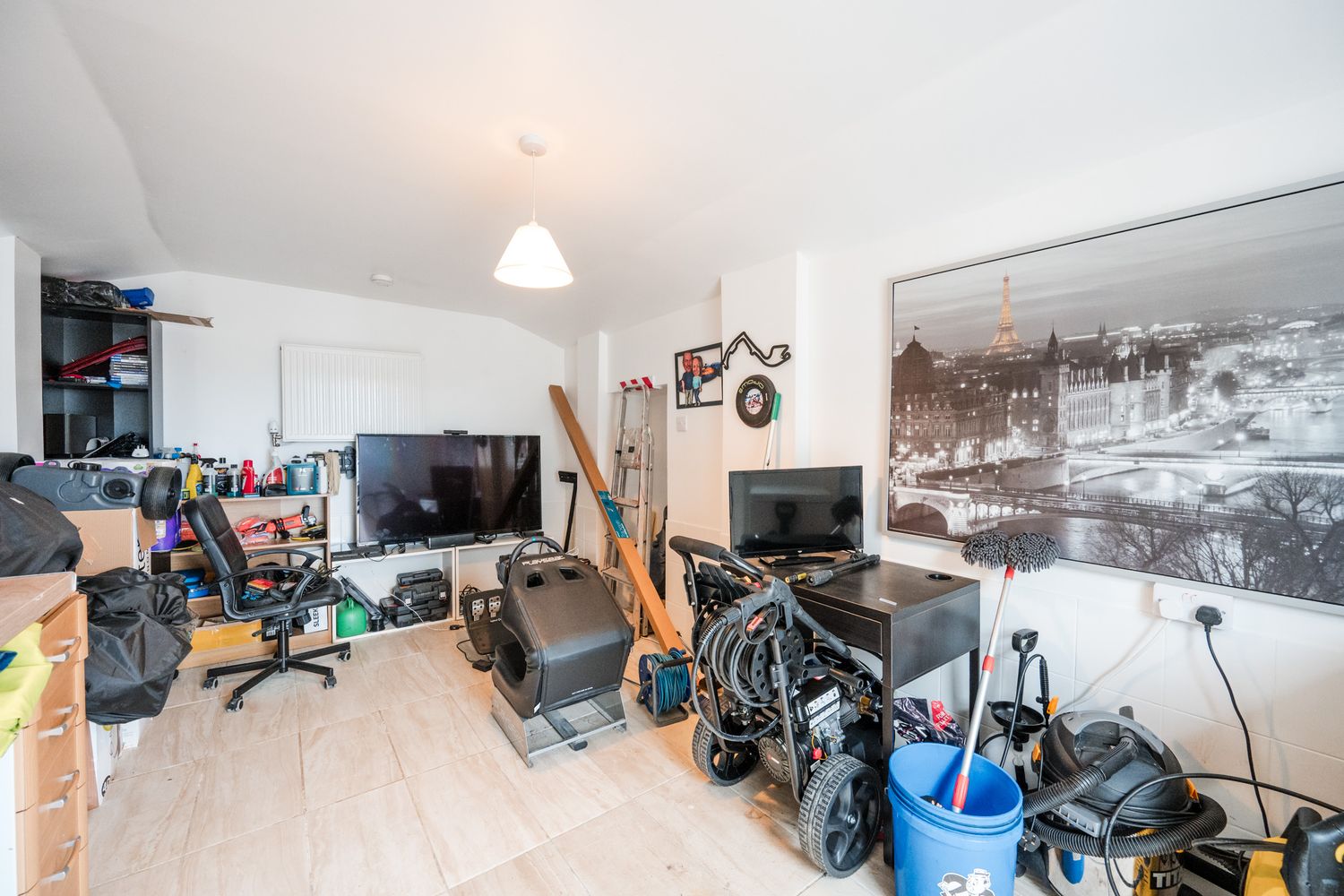 A cluttered room with computers, bikes, and various belongings showcasing a lived-in urban living space.