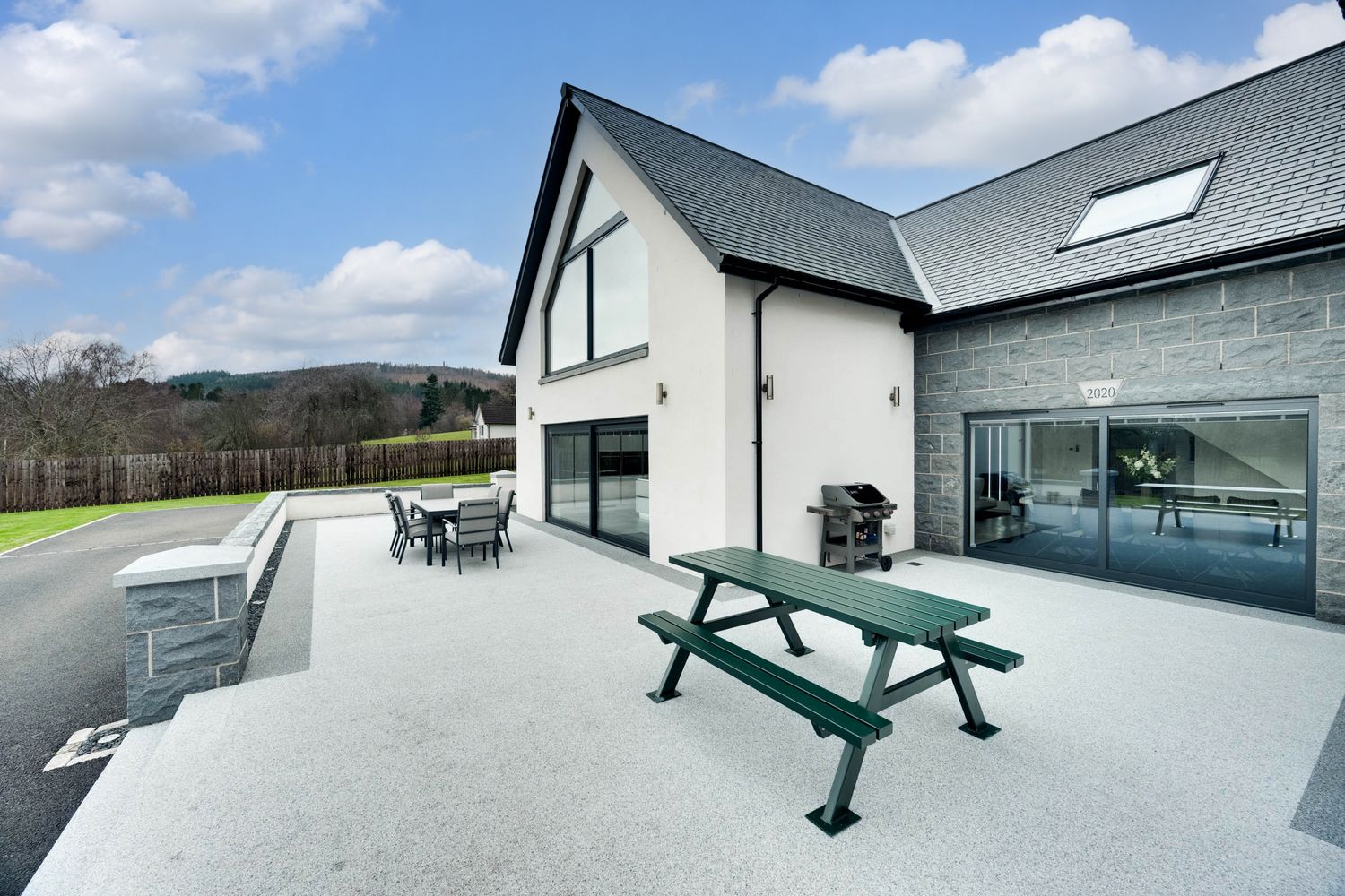A modern rooftop terrace with outdoor furniture and panoramic views of the surrounding landscape and mountains.