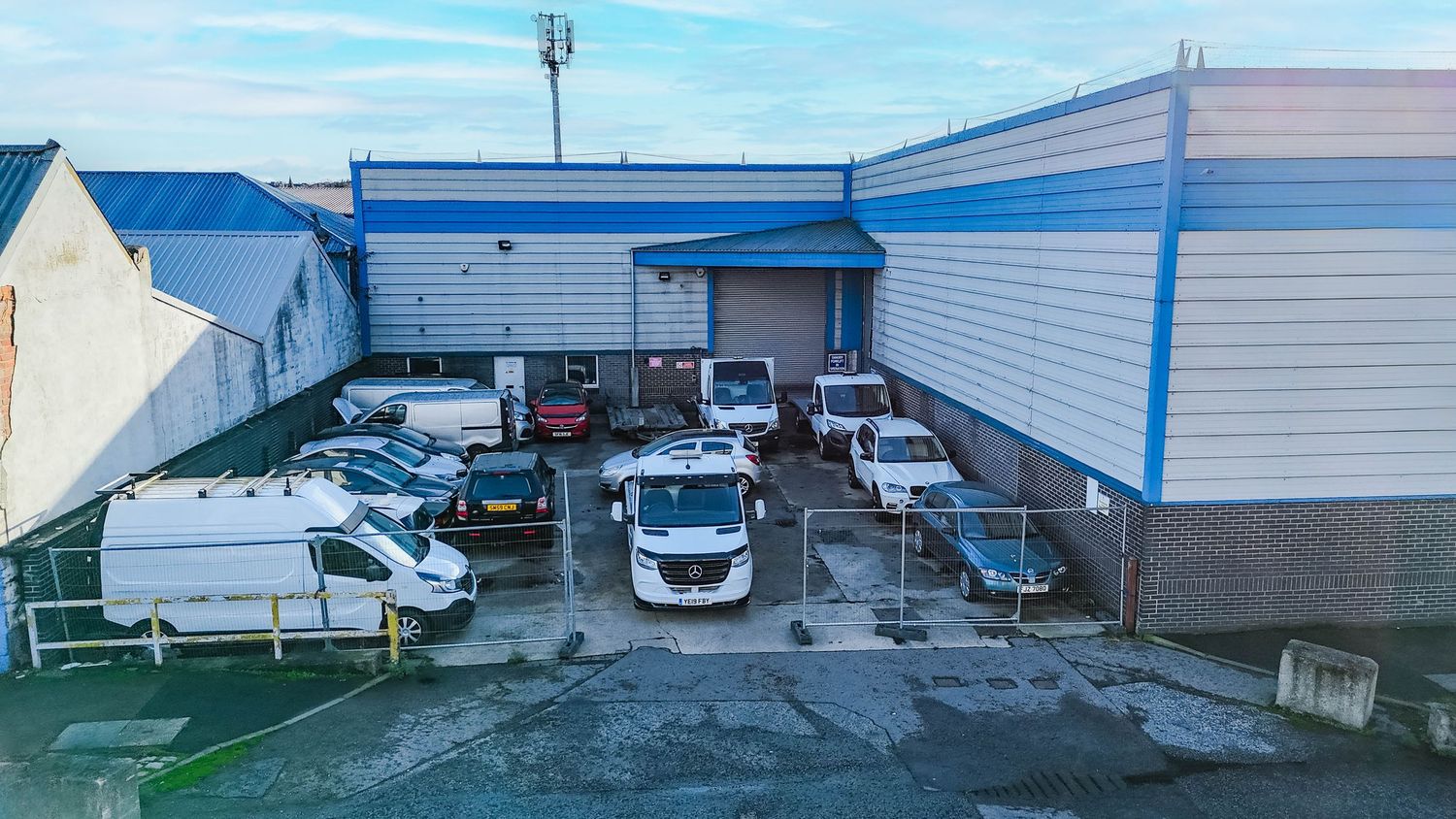 Wide exterior view of industrial buildings with loading bays under blue sky.