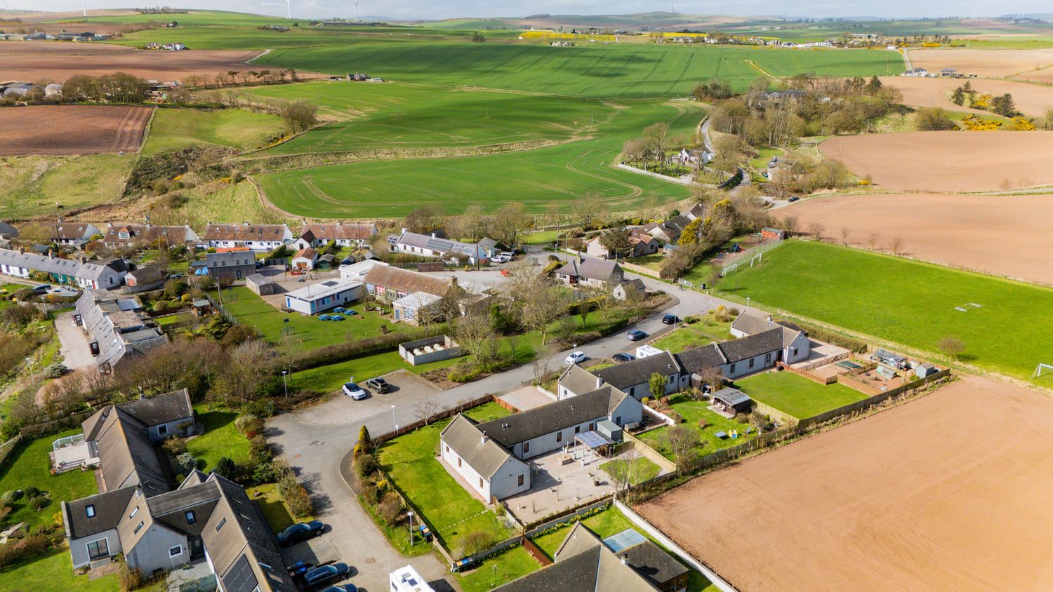 Aerial view of rural village with stone houses and green farmland in the countryside.