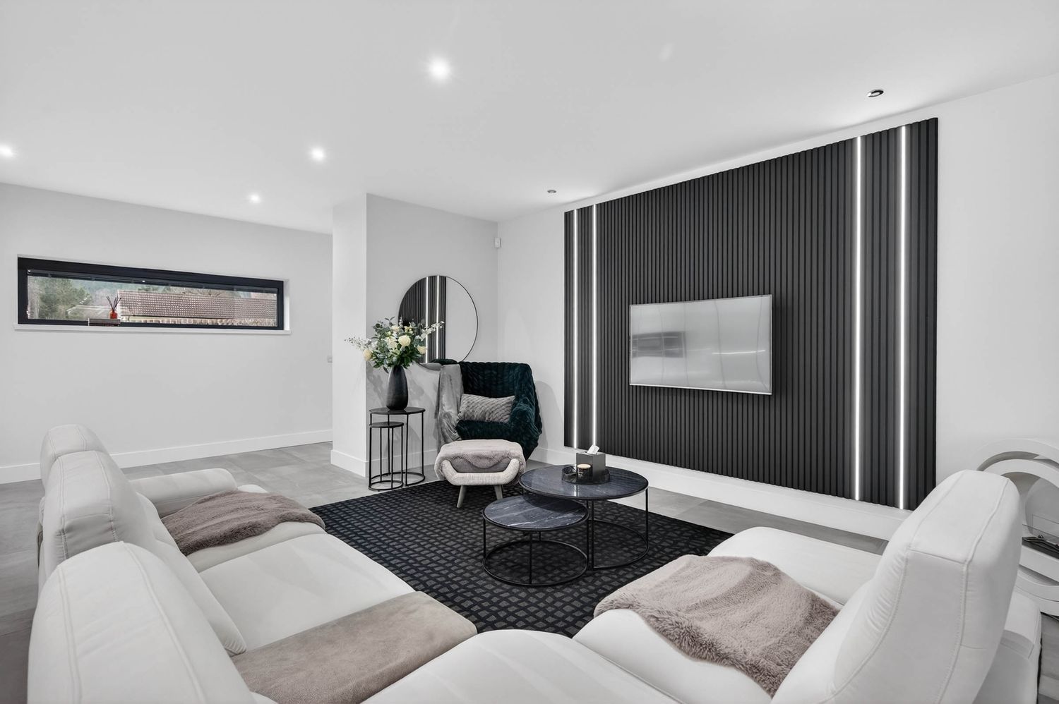 Contemporary living room with black accent wall, white couches, and modern decor on gray area rug.