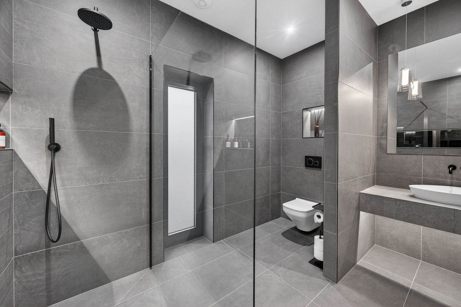 Modern grey bathroom interior with sleek shower enclosure, floating vanity, and recessed lighting in minimalist design.