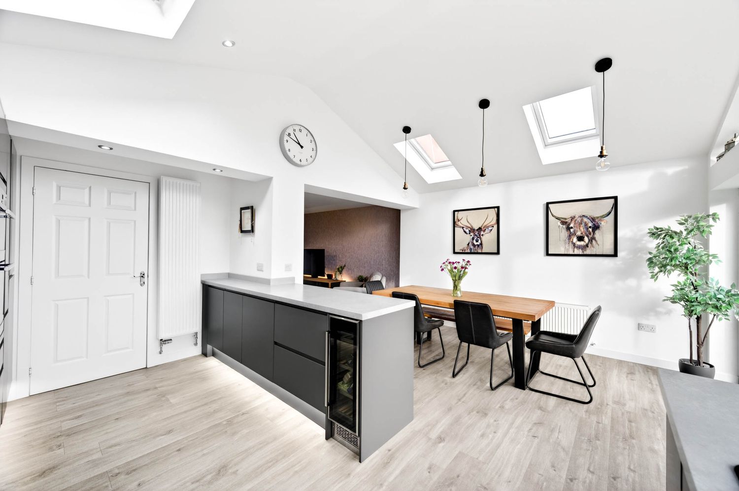 Open concept dining and living space with hardwood floors, skylights, and contemporary decor.