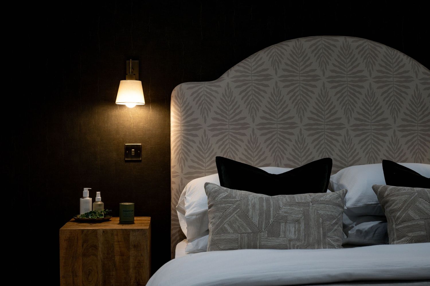 Elegant bedroom featuring textured wallpaper and modern bedding in neutral tones.
