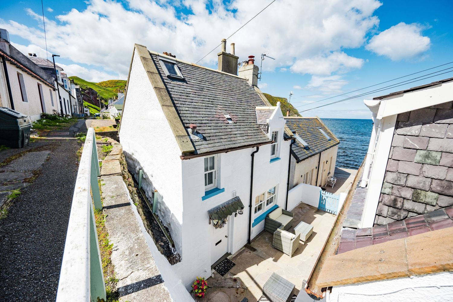 Charming white coastal cottage with slate roof overlooking the sea in a Scottish fishing village.