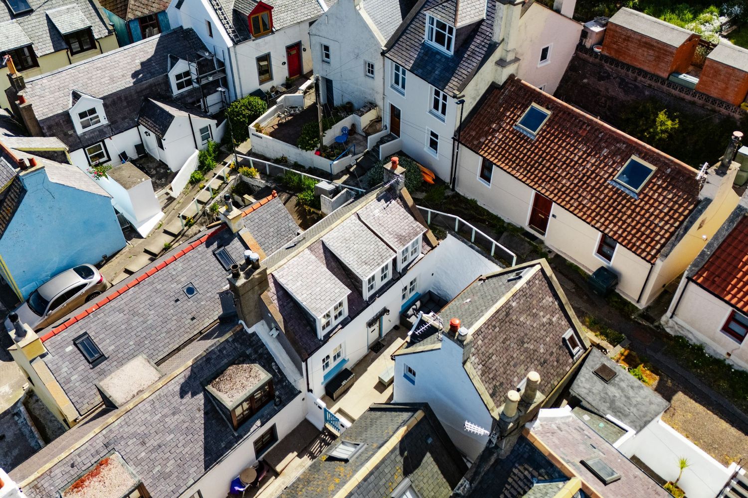 Bird's eye view of tightly packed coastal homes with white walls and varying rooftops.