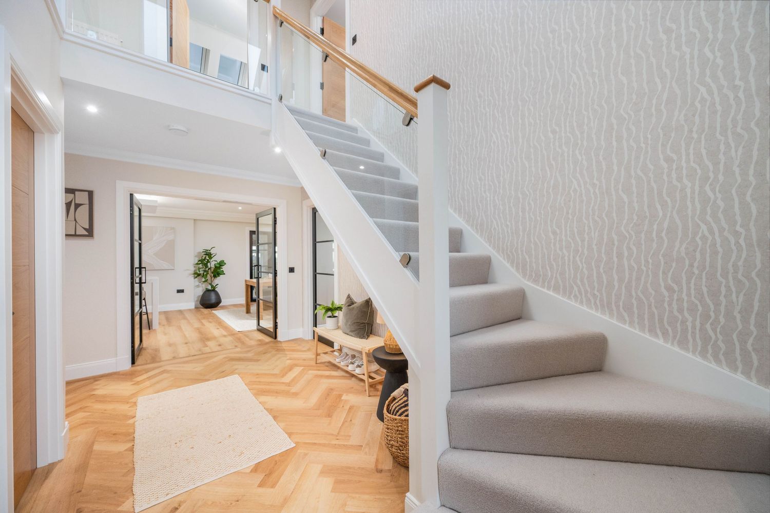 Clean white staircase with wooden handrail and natural light streaming in.