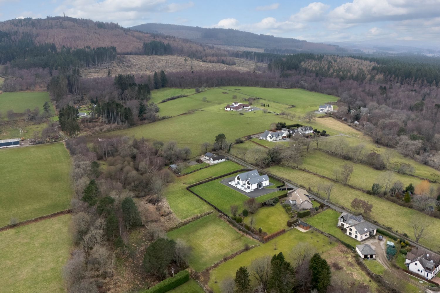 Panoramic landscape of verdant hillsides with white farmhouses nestled among patchwork fields and distant mountains.