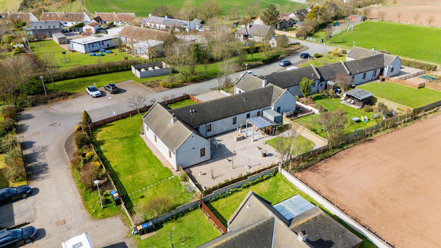 Aerial view of modern rural property development with expansive lawns and parking areas surrounded by farmland.