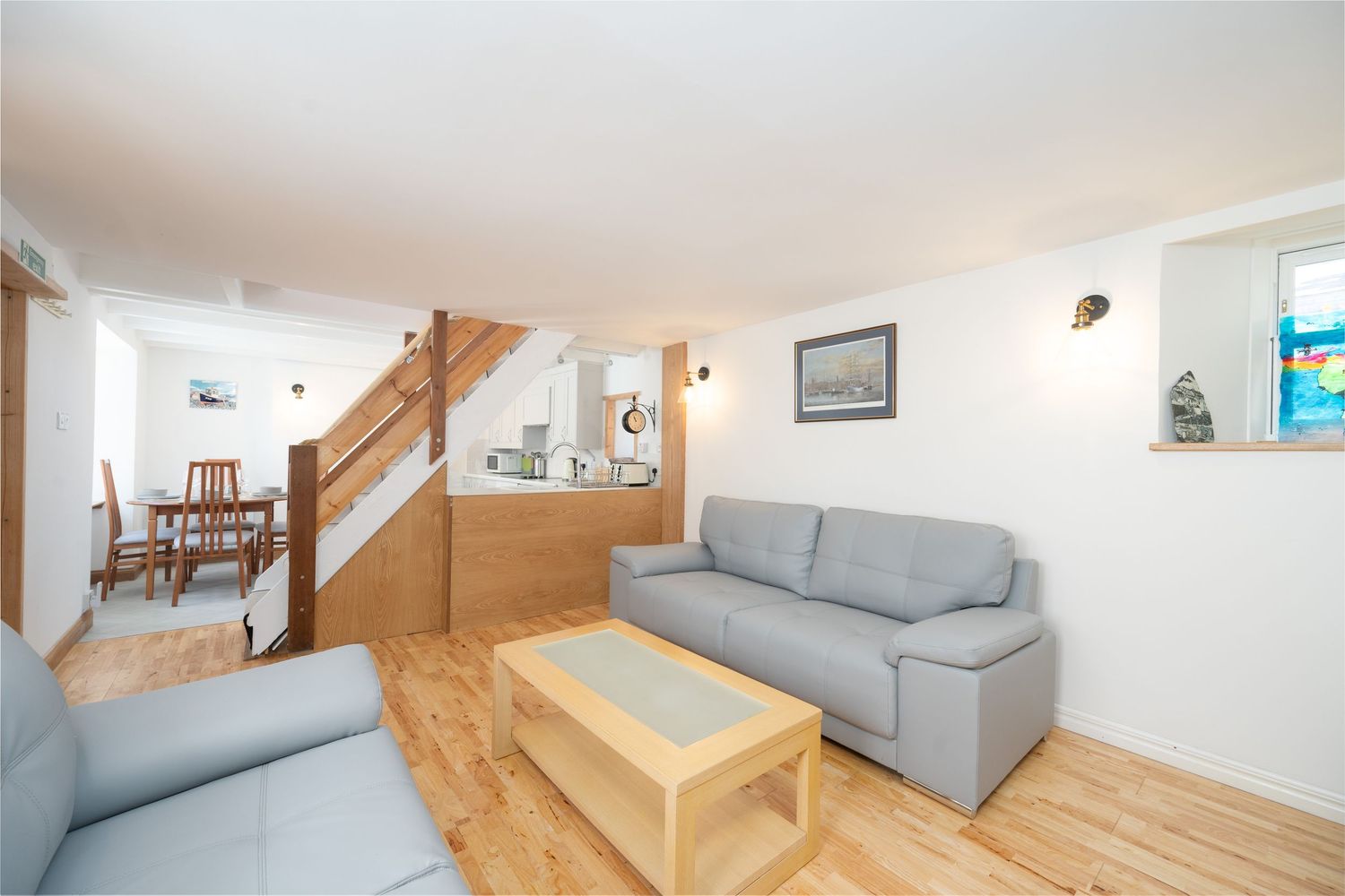 Modern living room interior with grey sofas, wooden coffee table and stairs in bright space.