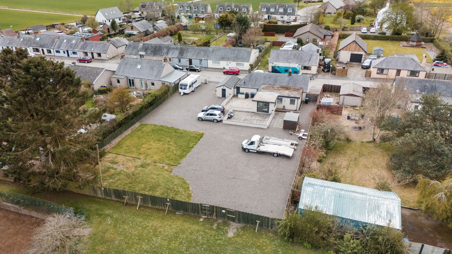 Aerial view of a camping site with RVs and mobile homes parked in an organized lot surrounded by green fields.