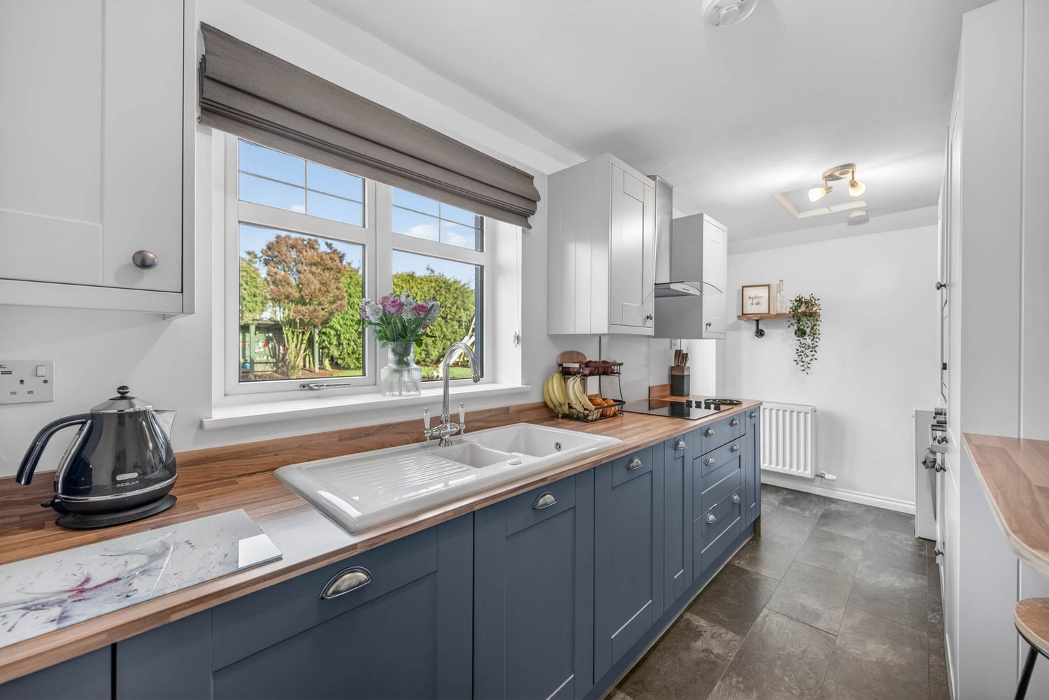 Modern kitchen with gray cabinets, wood countertops, and white walls showcasing a clean minimalist design.
