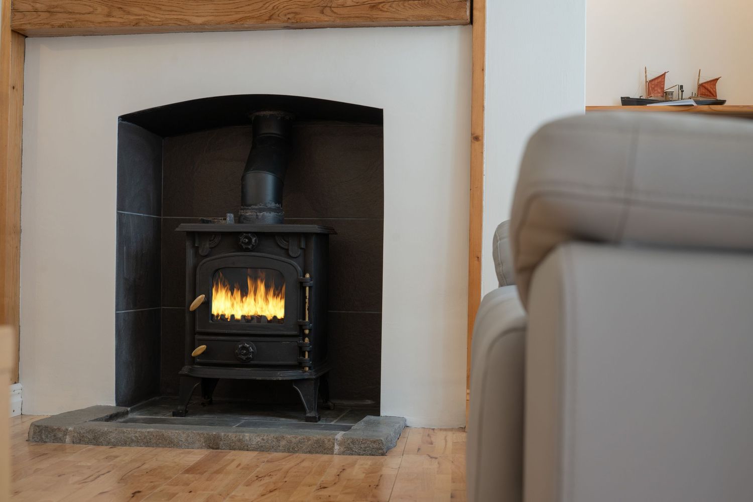 Black cast iron wood burning stove with glowing fire inside a white fireplace alcove.