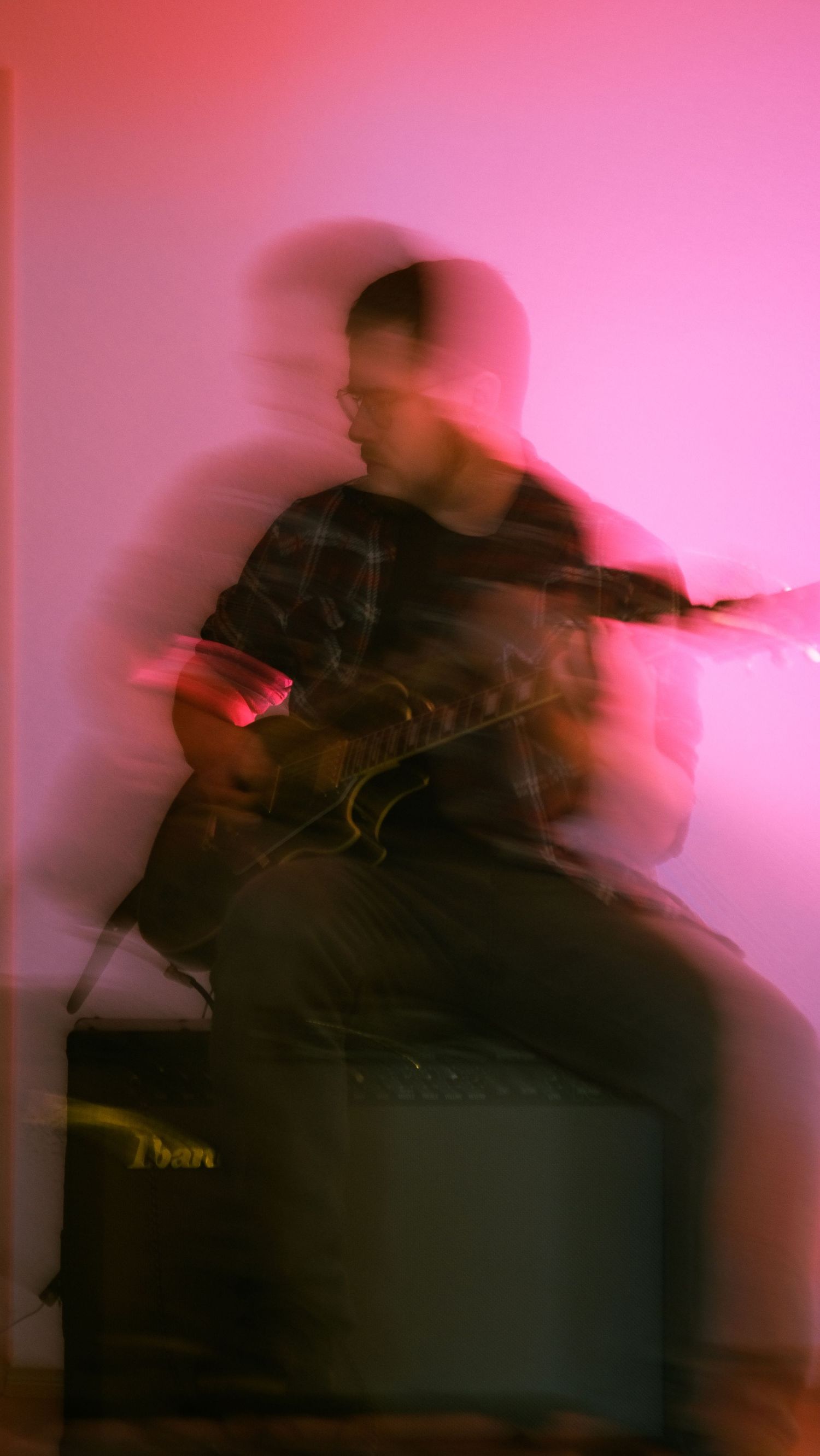 verschwommener Mann der Gitarre spielt vor rotem Licht