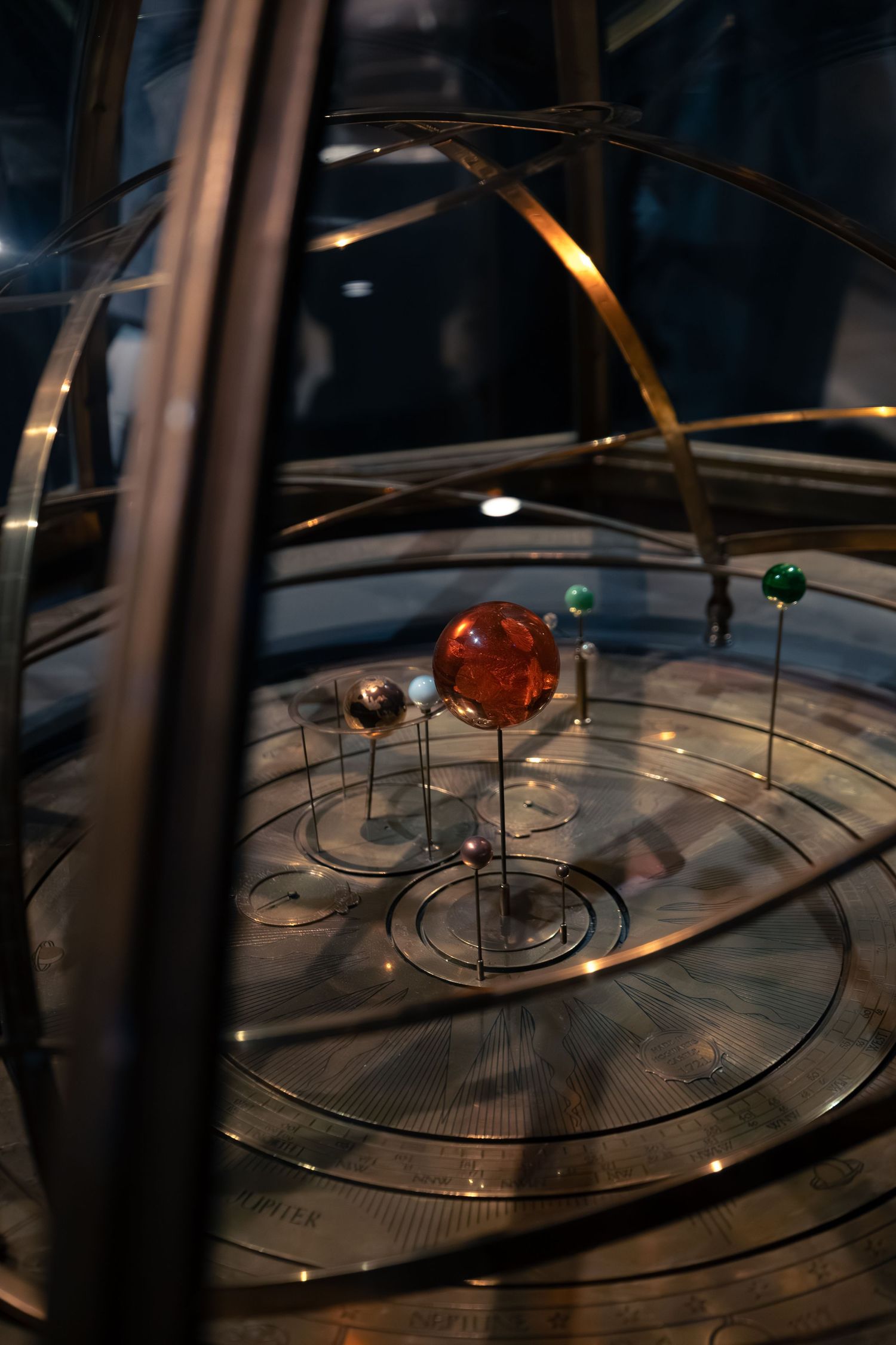 Ornate orrery mechanical solar system model with brass rings and colorful planet spheres.