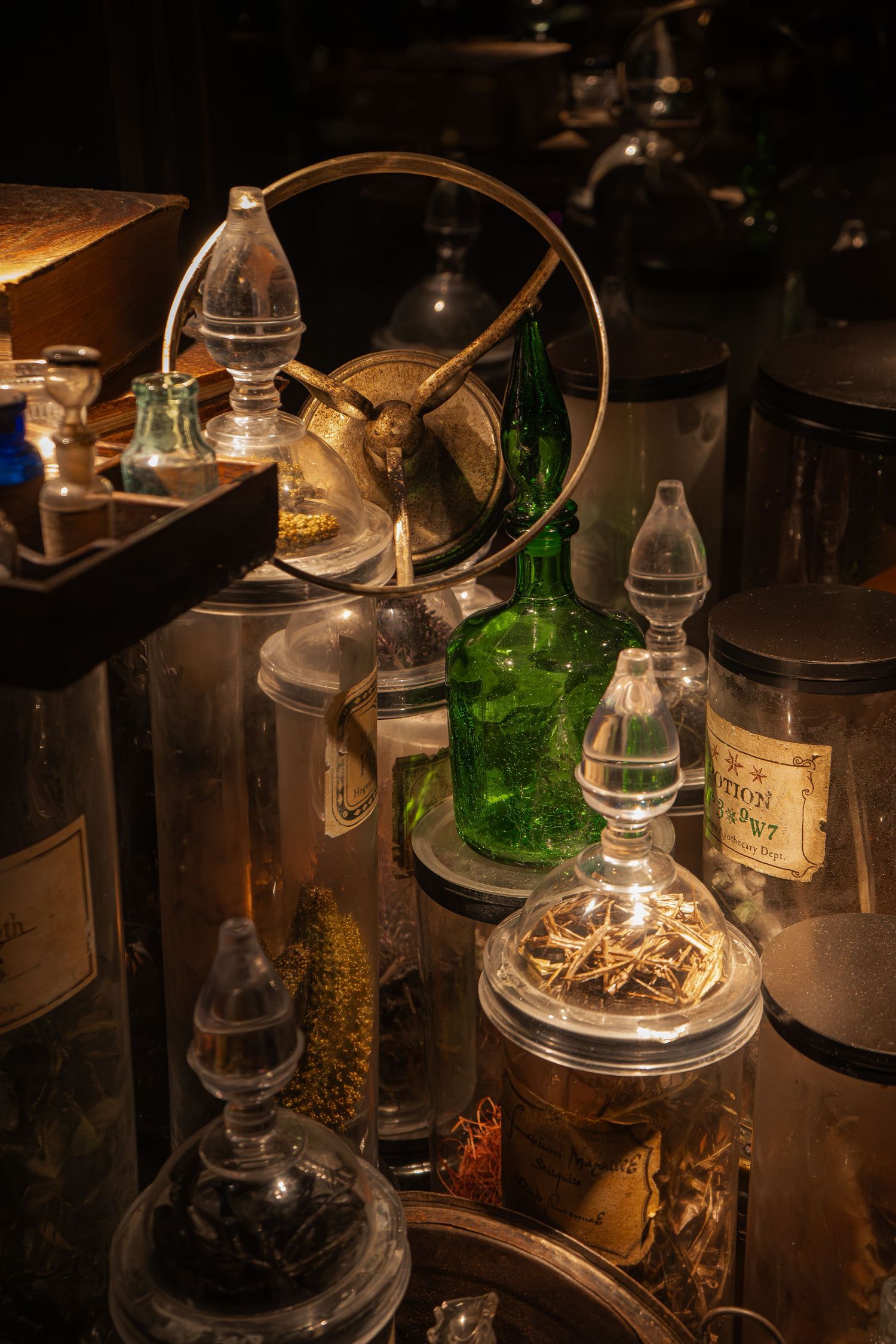 Antique apothecary collection of glass jars and bottles with dried herbs in dim light.