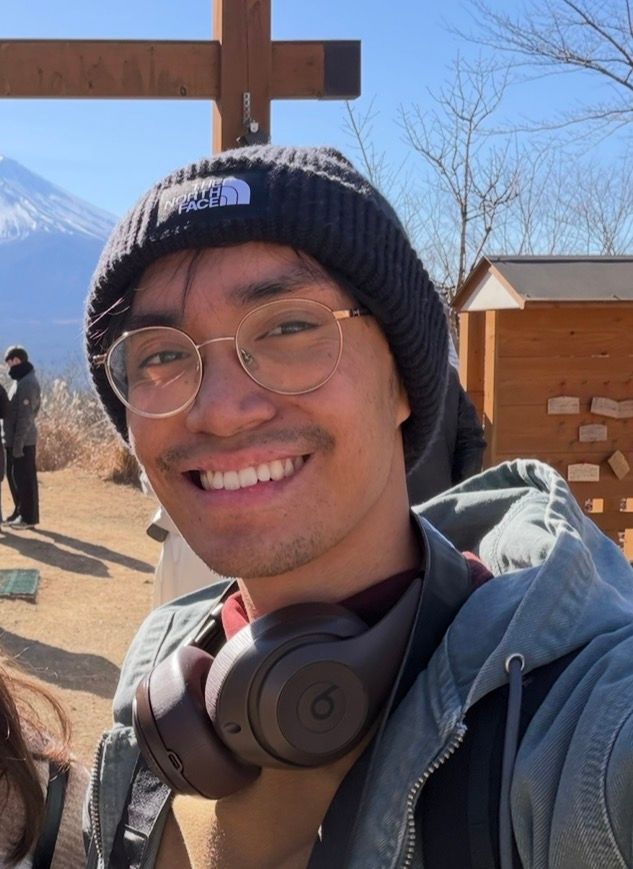 Smiling young man wearing a North Face beanie and Beats headphones outdoors near Mount Fuji, Japan.