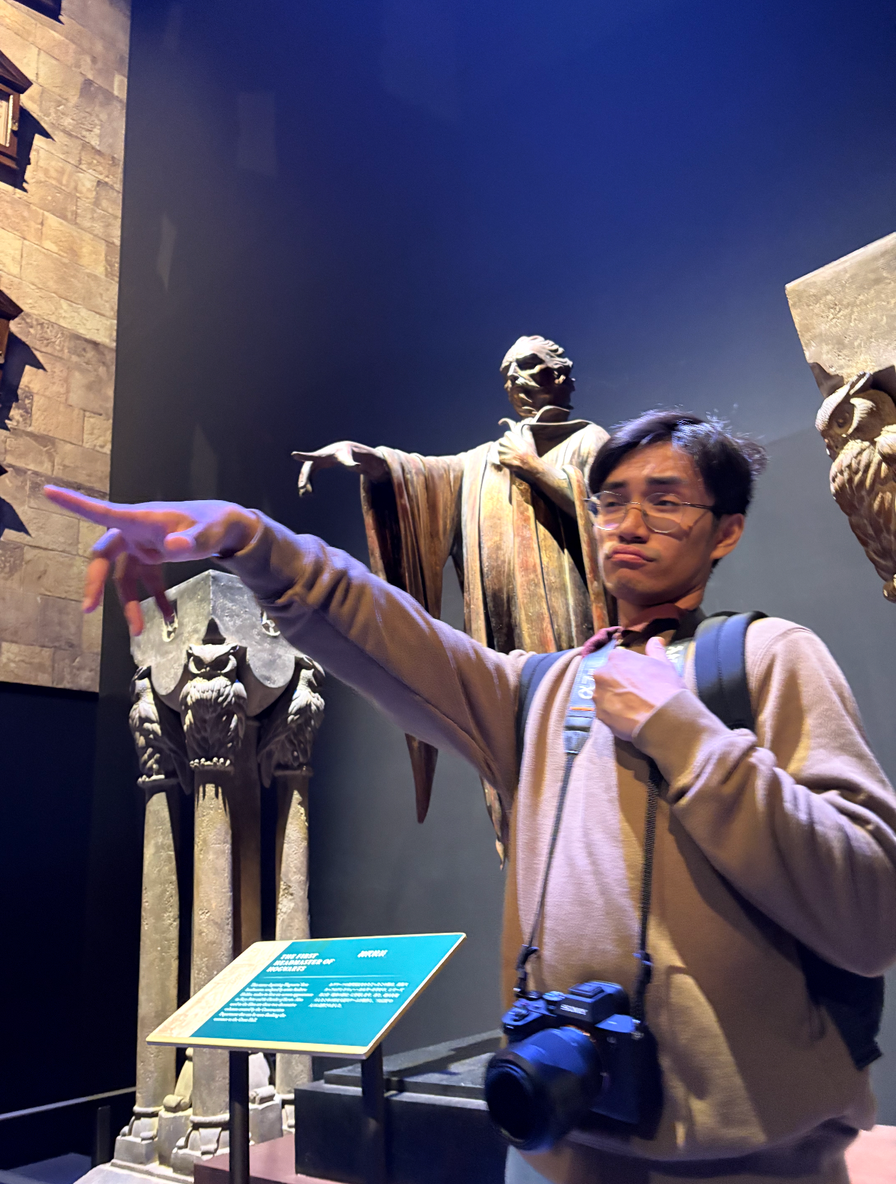 Tourist pointing at a wizard statue display at the Harry Potter Studio Tour exhibition.