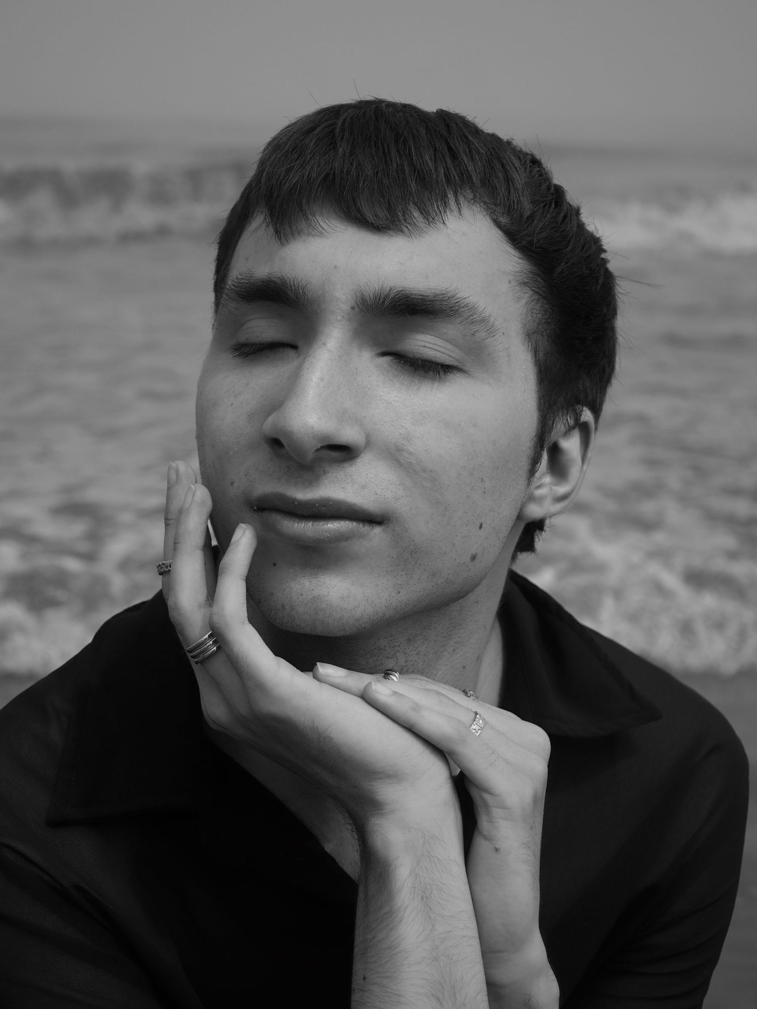 Adam posing in black and white on a beach.