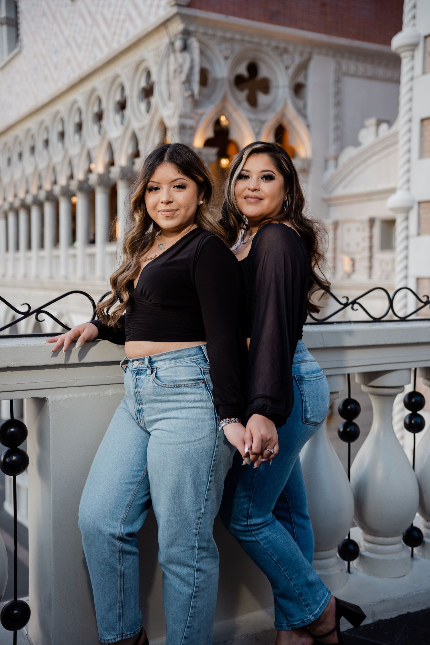 Two young women in matching black tops and jeans pose back-to-back at The Venetian in Las Vegas.