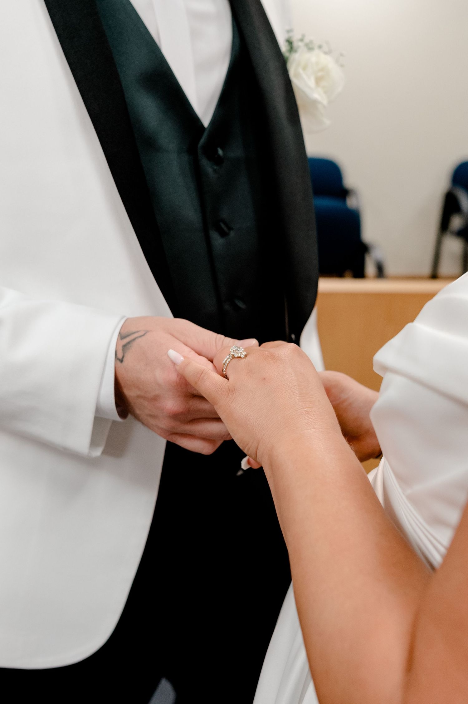 Groom placing a diamond engagement ring on bride's finger during wedding ceremony exchange of vows.