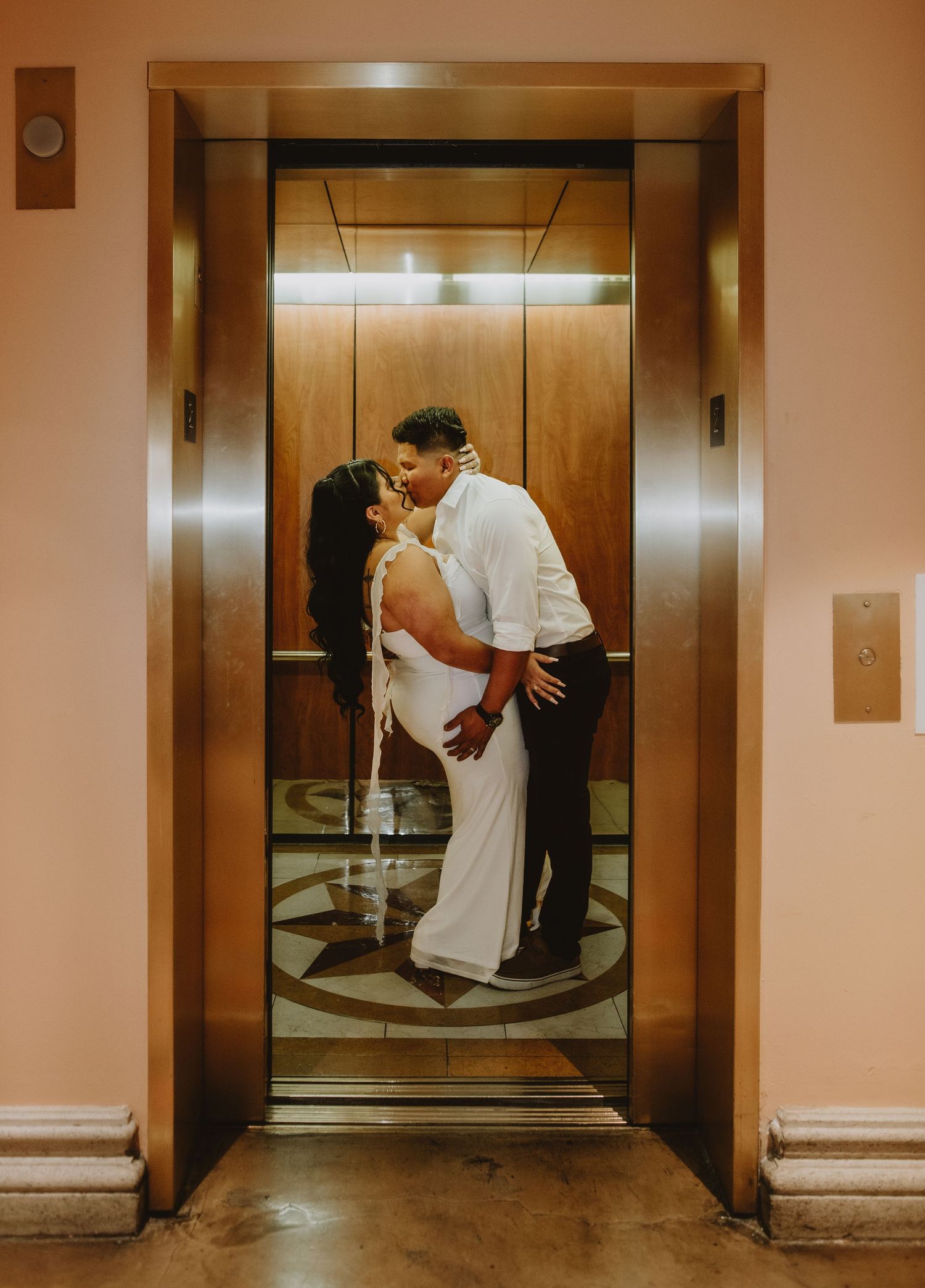 Bride and groom sharing a passionate kiss inside a gold elevator at The Venetian Las Vegas.