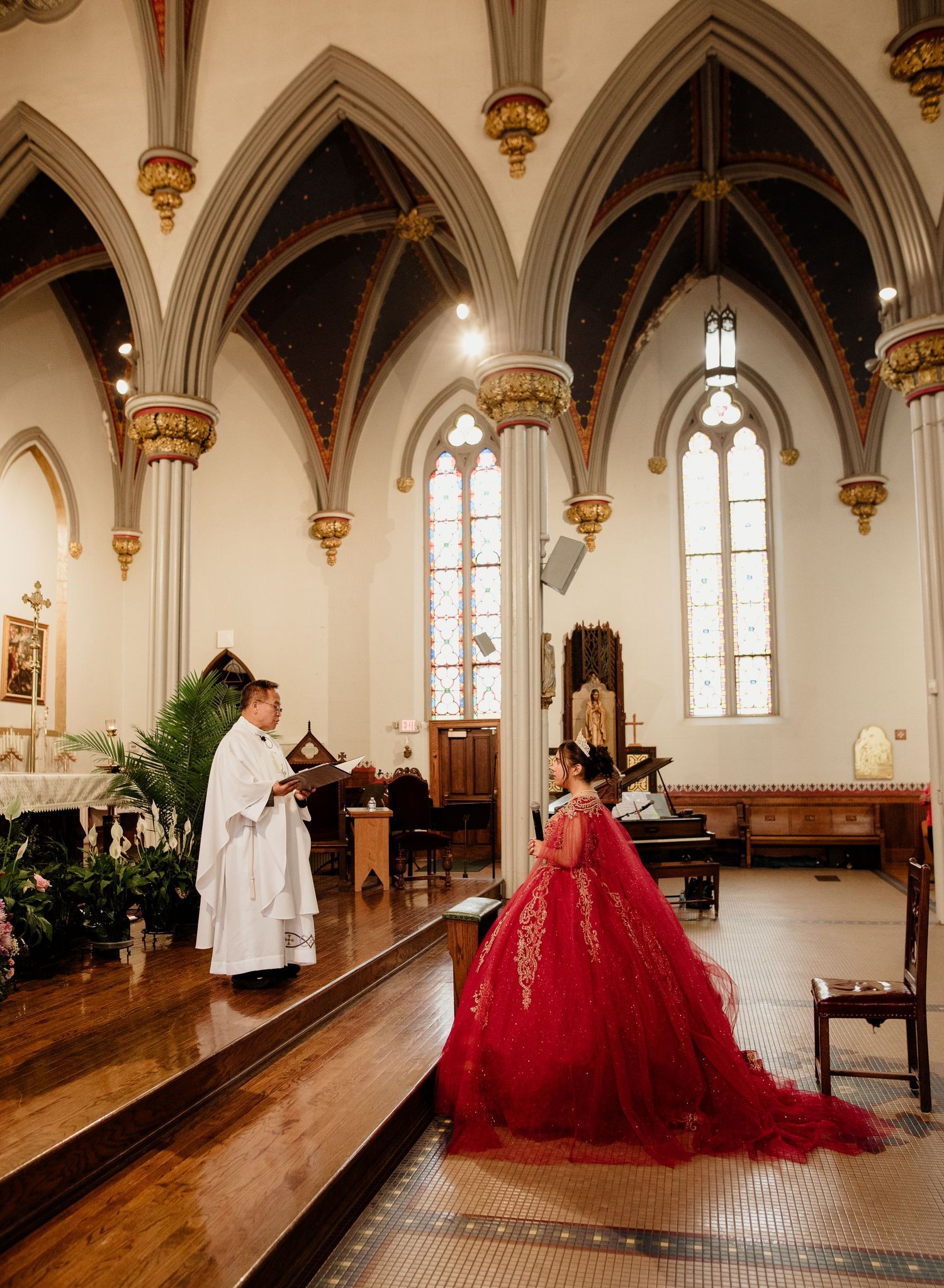 Priest reads from book during quinceañera Mass in Gothic-style church.