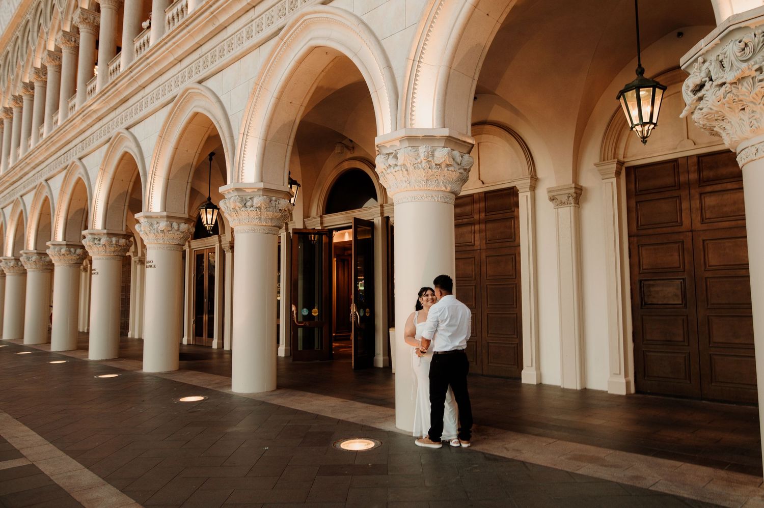 Couple shares romantic moment under elegant white arched colonnade at The Venetian Las Vegas.