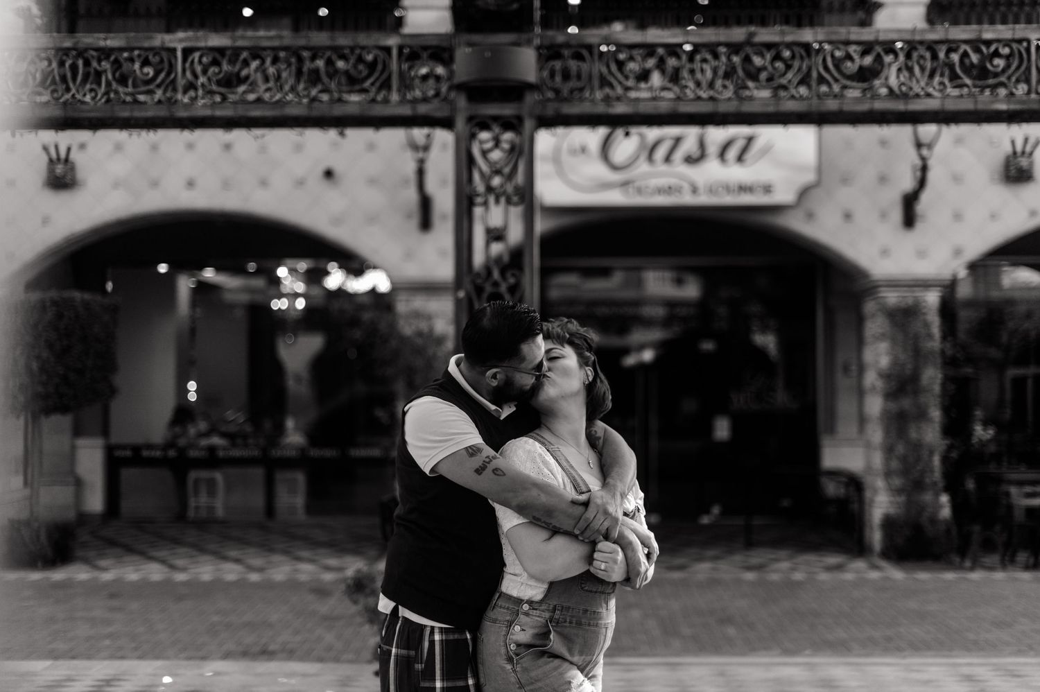 Black and white photo of couple sharing a passionate kiss outdoors at night.
