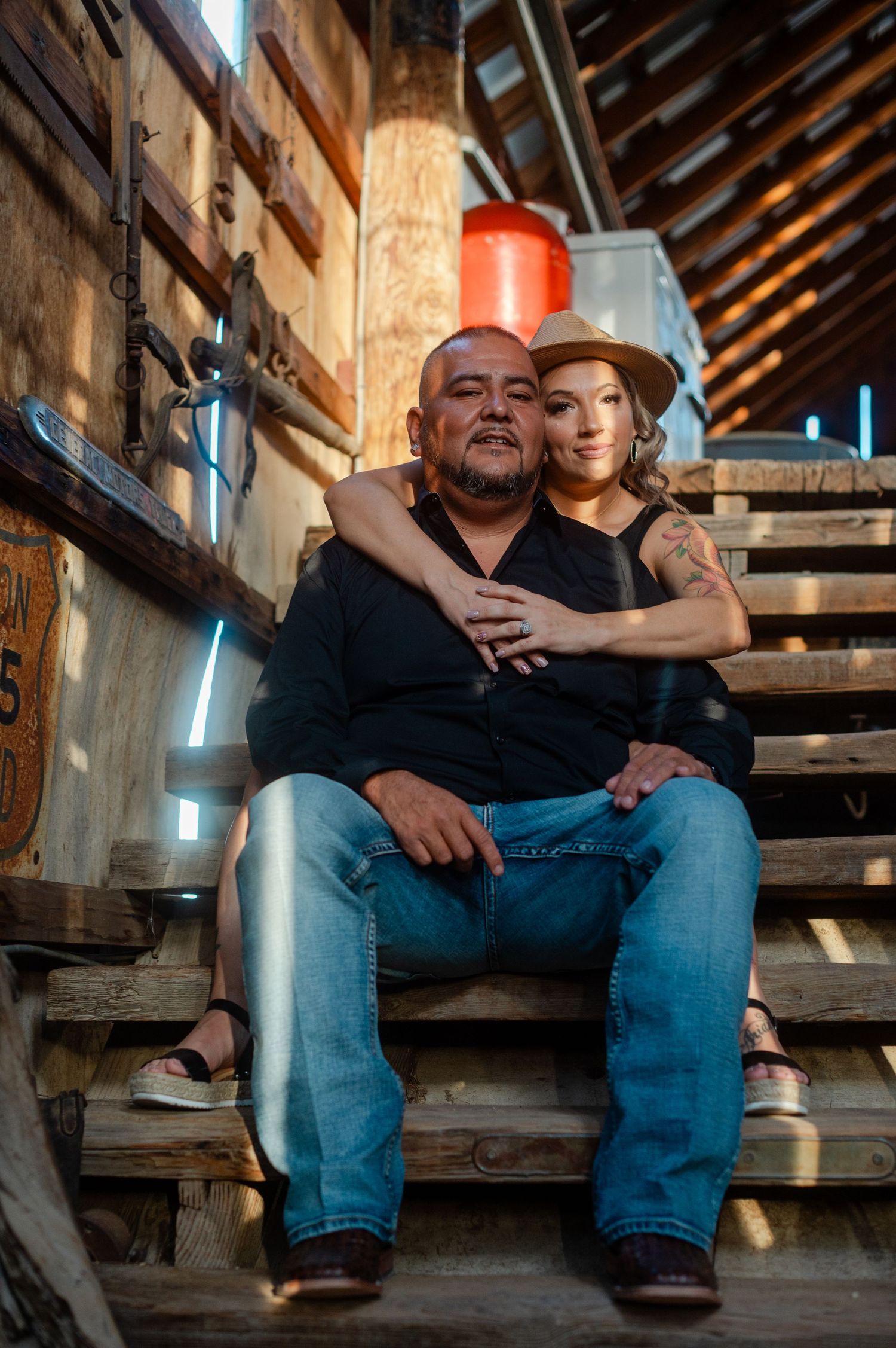 Couple sitting closely together on weathered wooden steps in a rustic interior setting.