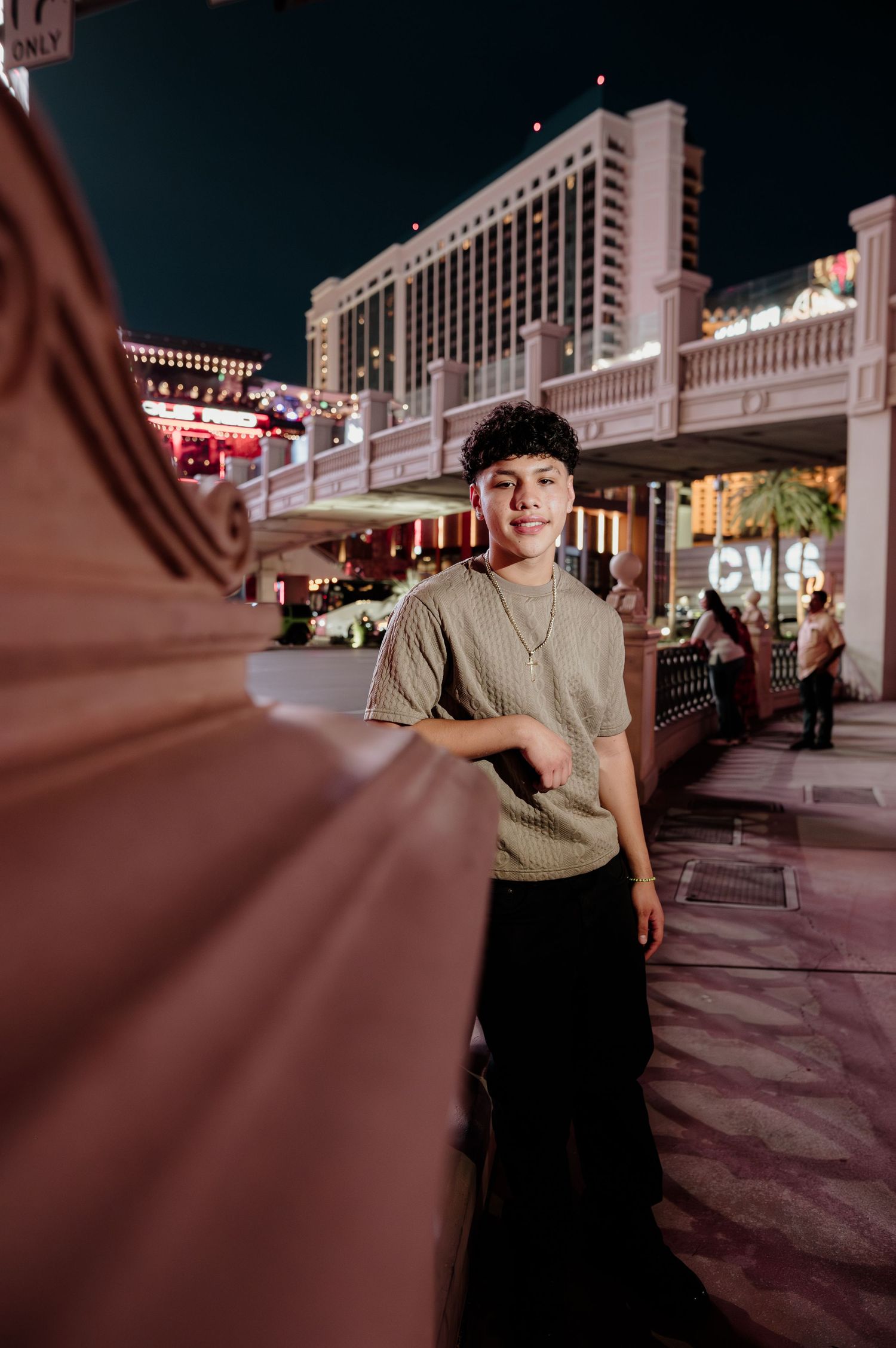 Young man smiling confidently at night on the Las Vegas Strip with bright city lights behind him.