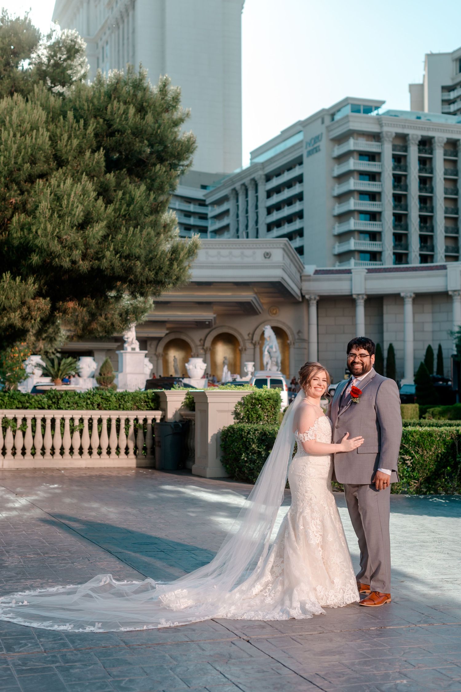 Bride and groom pose together outdoors at Caesars Palace Las Vegas with a flowing cathedral veil.