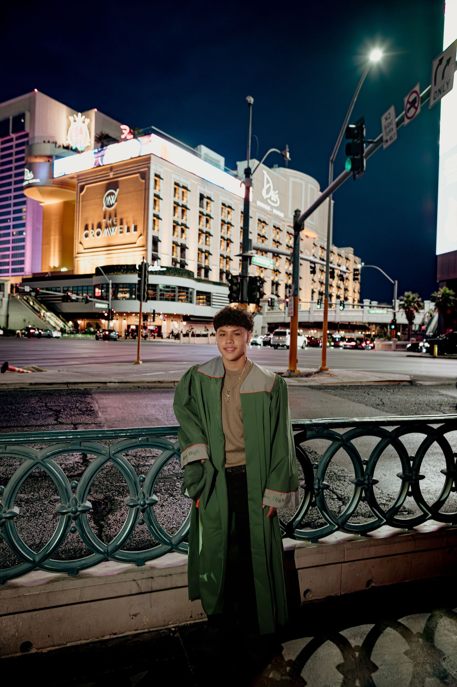 Smiling young man in green coat stands on Las Vegas street corner at night.
