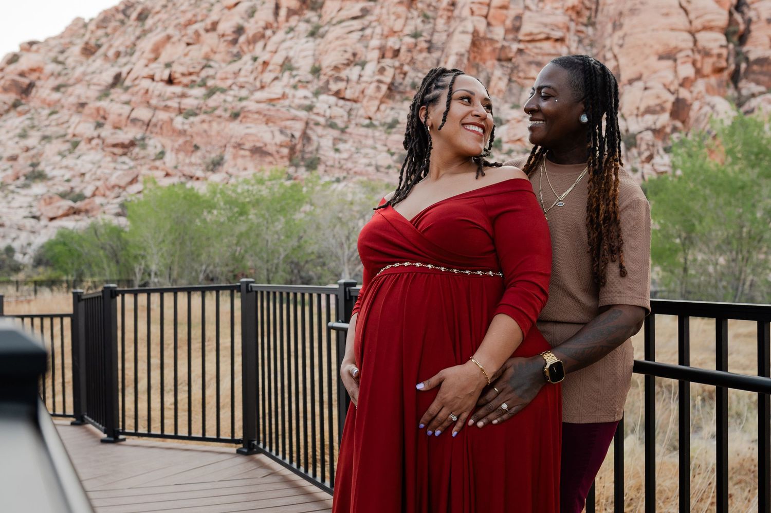 Couple sharing a joyful moment during maternity photos at Red Rock Canyon overlook.